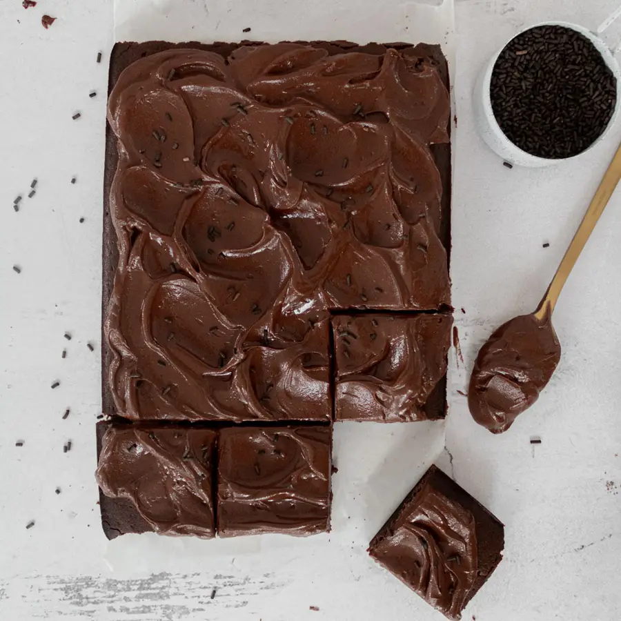 Torta de chocolate rectangular con ganache vista desde arriba, con cacao y una cuchara