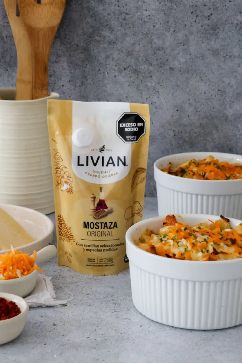 Bowl de mac and cheese junto a un sachet de mostaza Livian y un trozo de queso