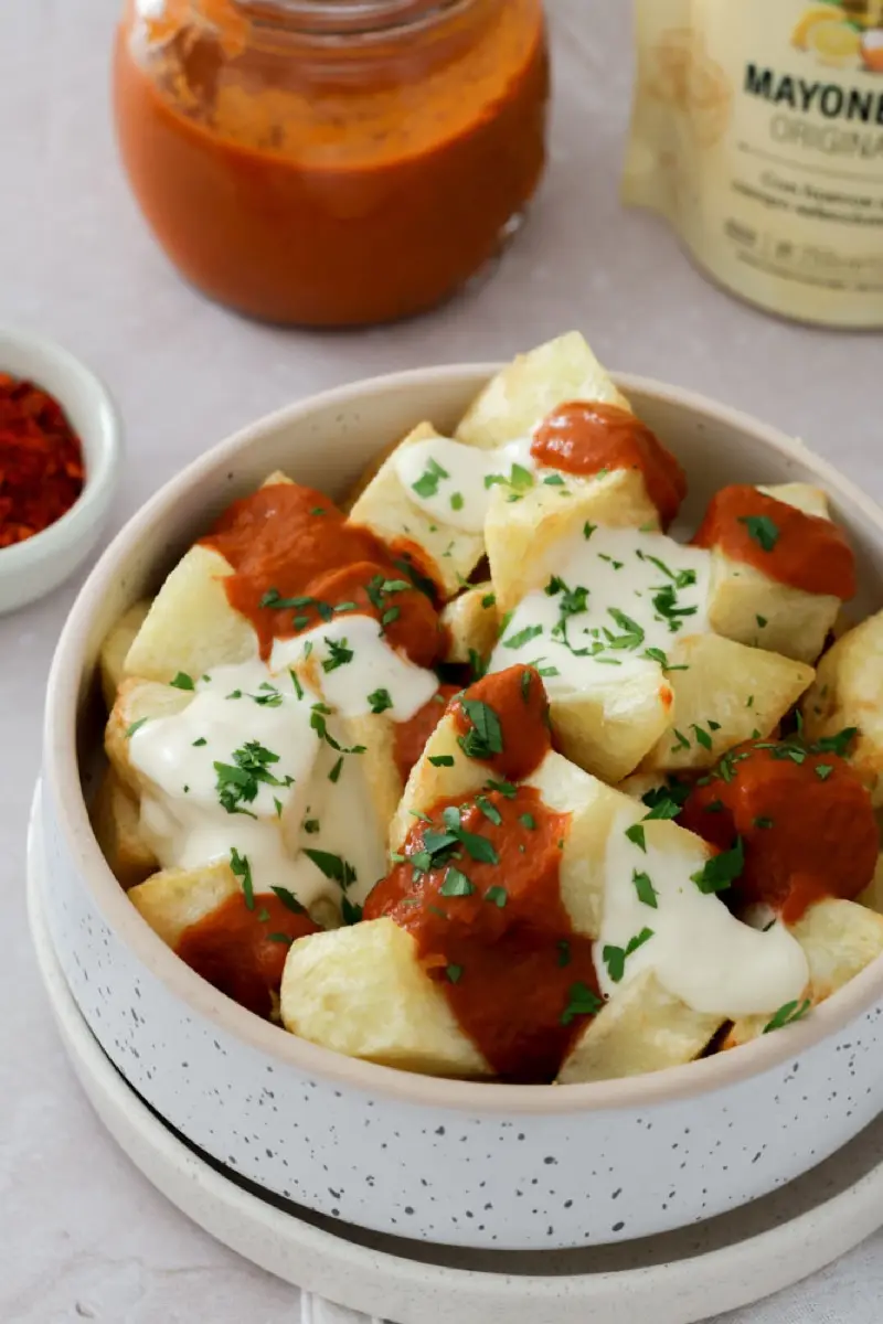 Detalle de papas bravas con salsa brava y salsa blanca