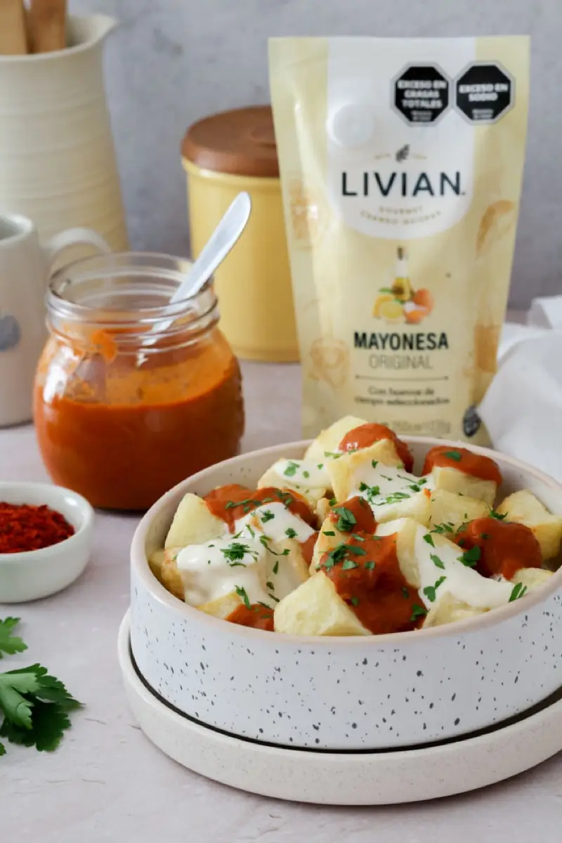 Bowl de papas bravas con un sachet de mayonesa Livian y un frasco de salsa