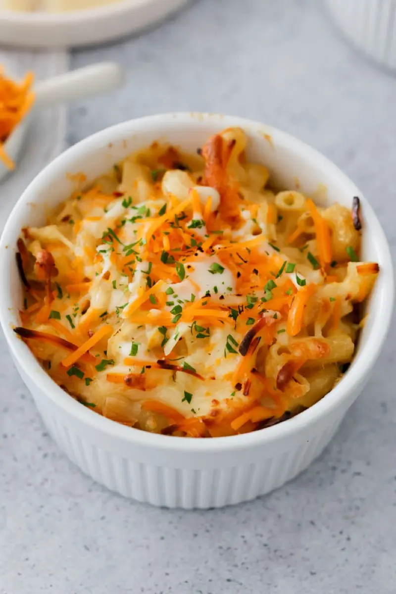 Gratinated mac and cheese in a white bowl with grated cheese and parsley, produced for Livian