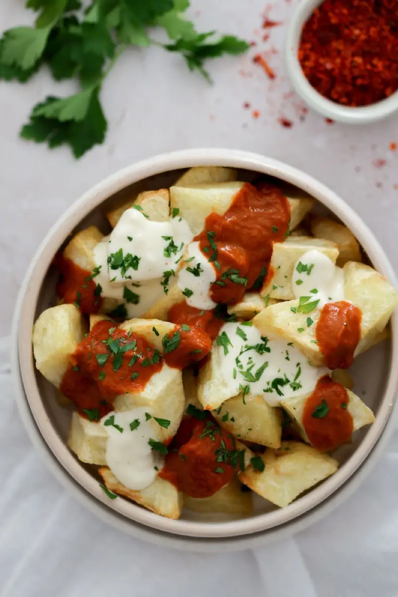 Papas bravas con salsa picante y salsa blanca en un bowl moteado, producción para Livian
